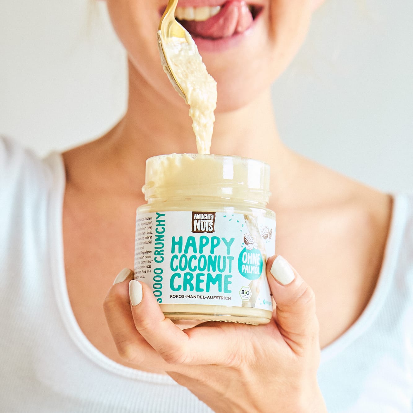 Frau löffelt Happy Coconut Creme aus Glas